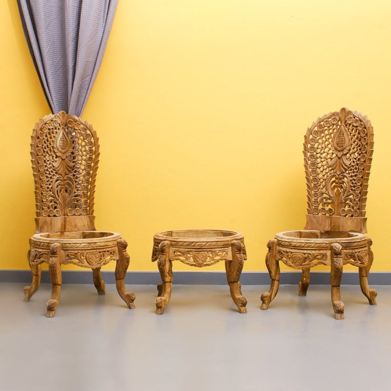Pair of hand-carved wooden chairs with a matching round table against a yellow wall