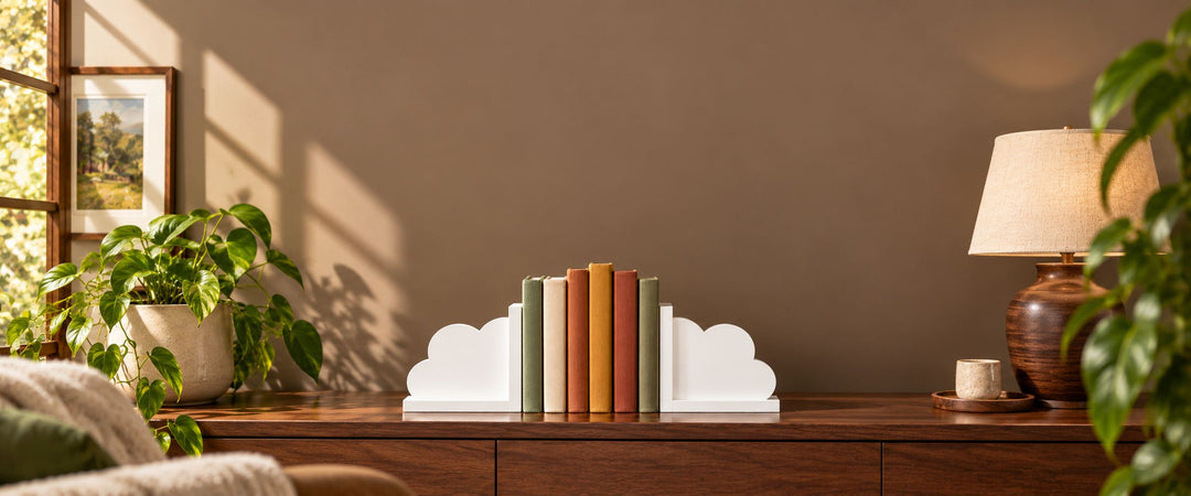 Pair of white cloud-shaped bookends holding muted-colour books on a walnut study shelf