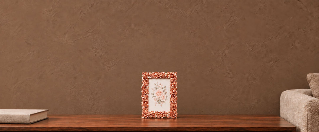 Rose-gold floral relief photo frame with a pink rose print on a walnut console in a naturally lit neutral lounge