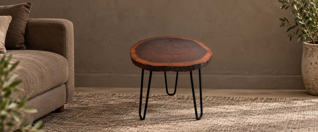 Dark natural wooden log slice side table with three black hairpin legs beside a brown sofa