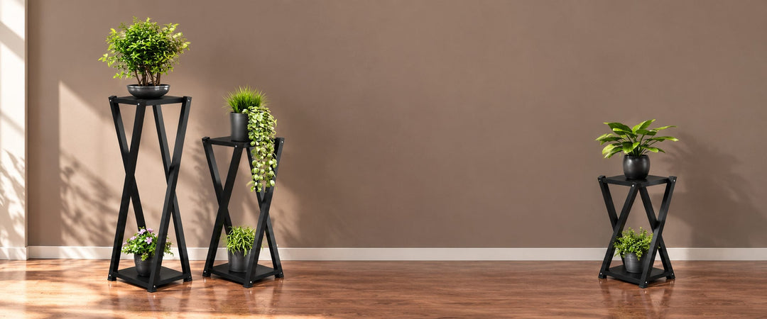 Three black X-frame Valentinus plant stands in different heights with potted greenery in a daylit room