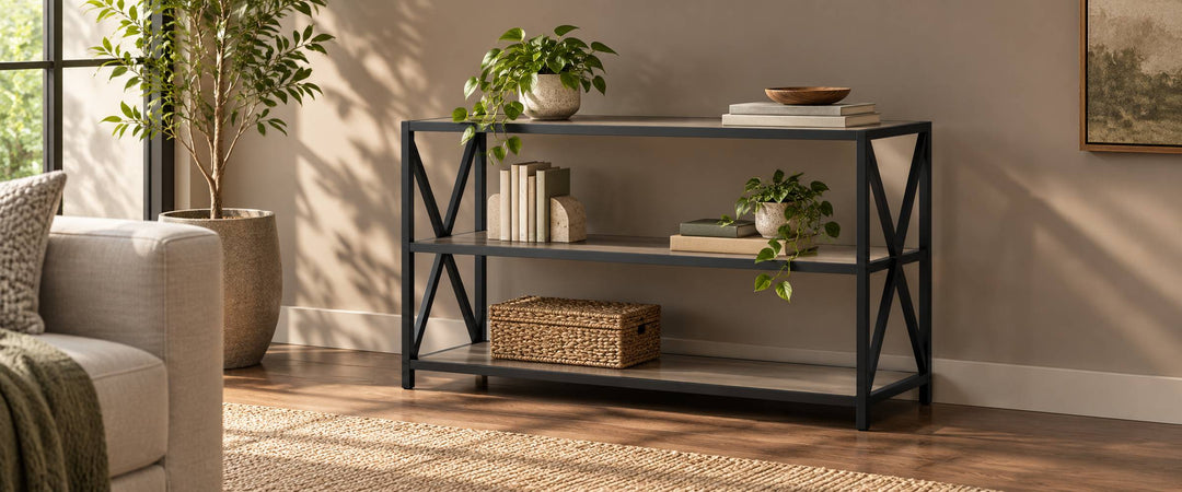 Three-tier wood and black metal X-frame console rack with books and plants in a sunlit living room