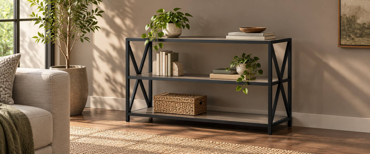 Three-tier wood and black metal X-frame console rack with books and plants in a sunlit living room