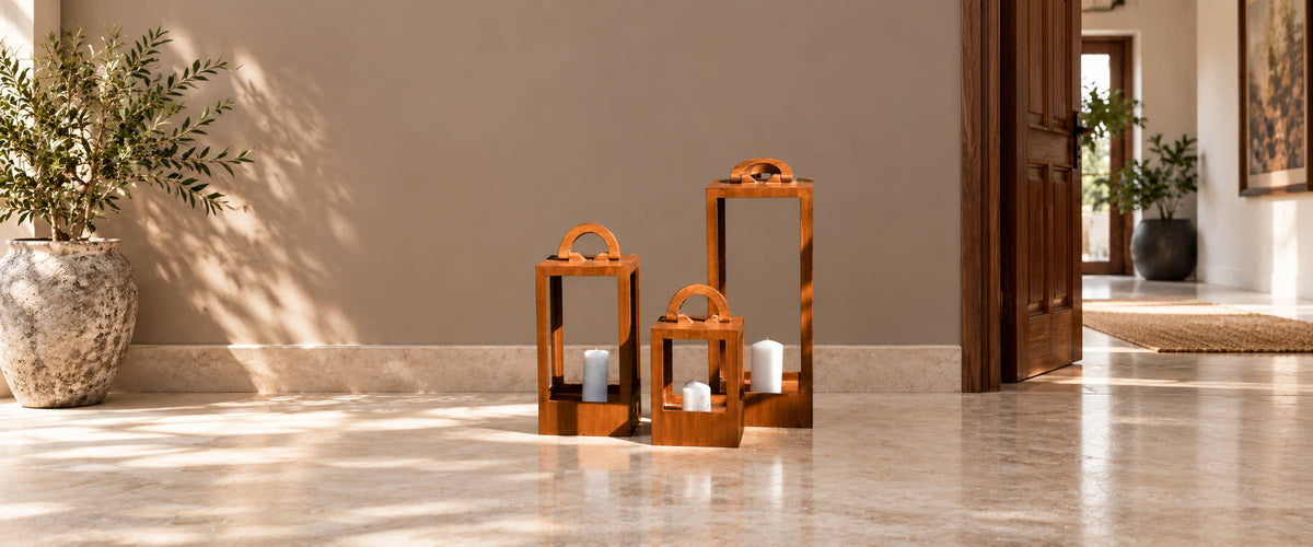 Three graduated wooden lantern candle holders with unlit white candles in a warm neutral entryway