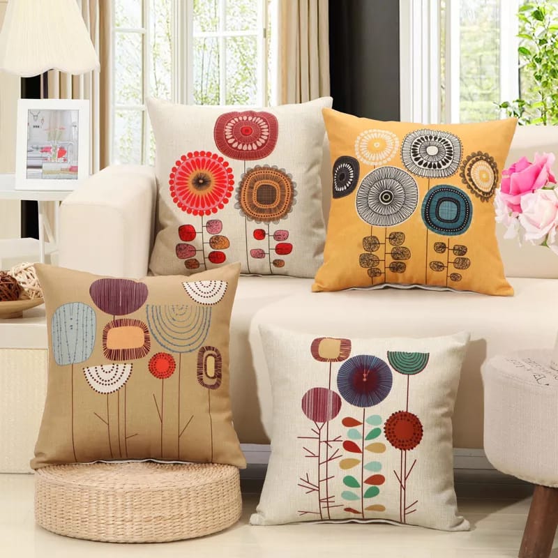 Four floral-print cushion covers in cream, mustard and beige arranged on a light sofa