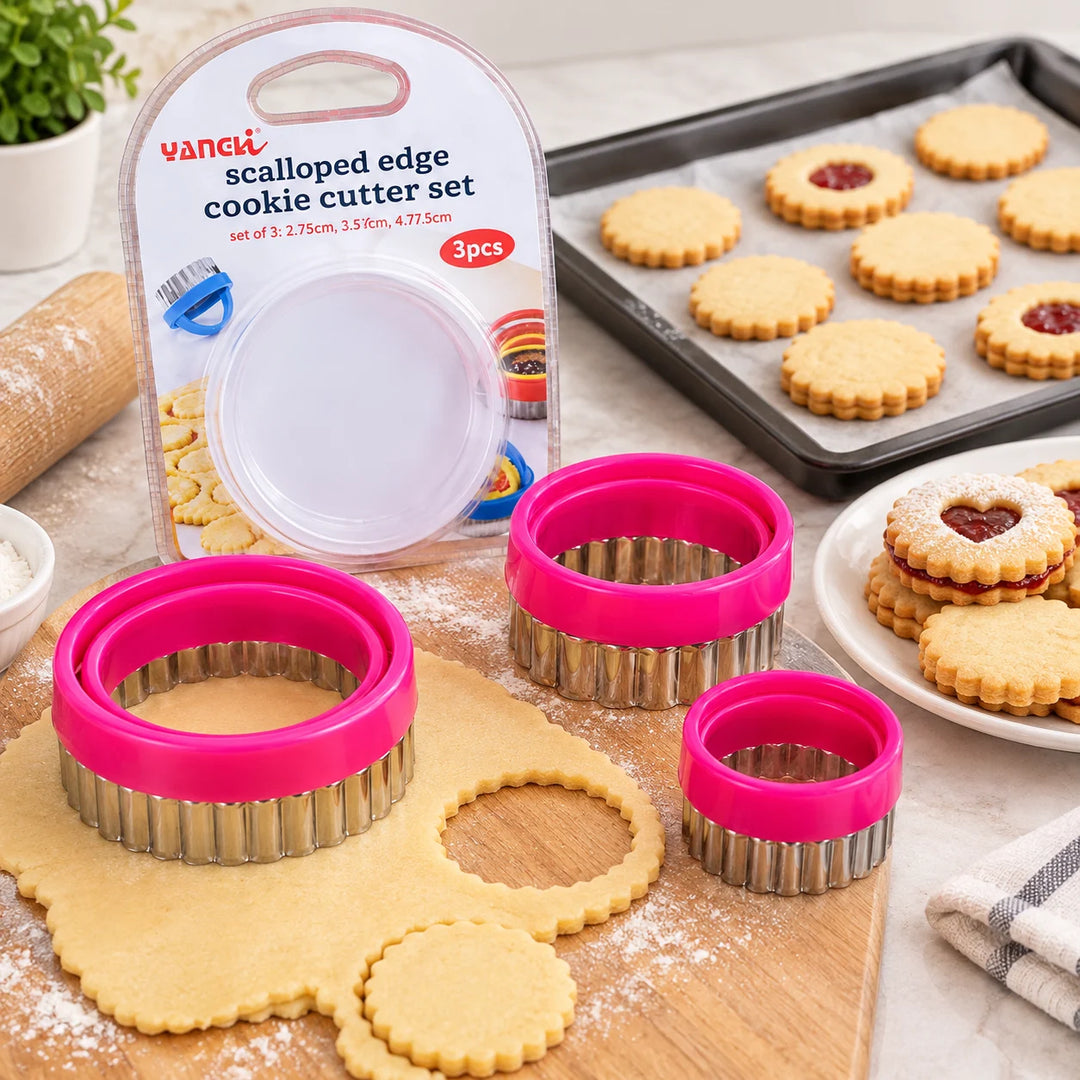 Three pink-handled round cookie cutters with dough and baked cookies