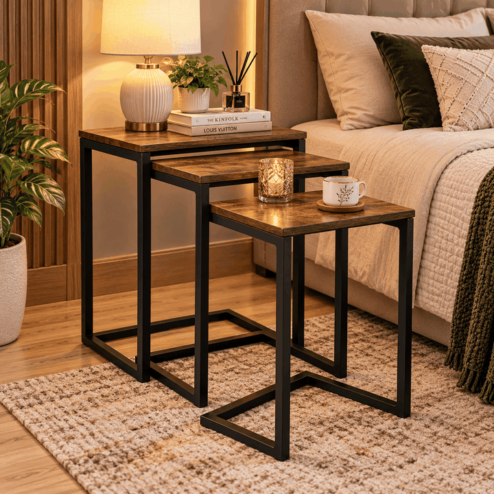 Three brown-topped nesting side tables with black frames beside a bed