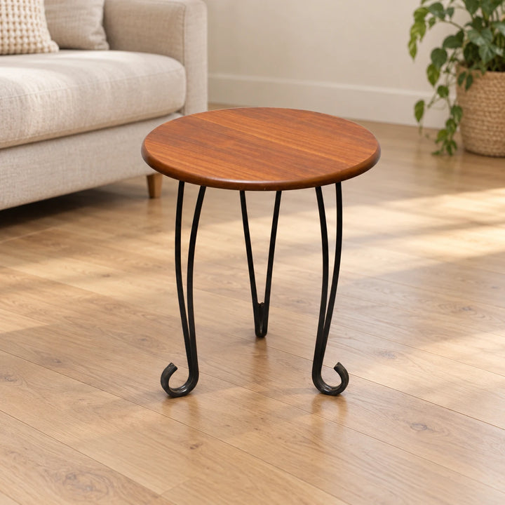Alaskal Style 1 round side table with brown top and curled black feet in a sunlit room