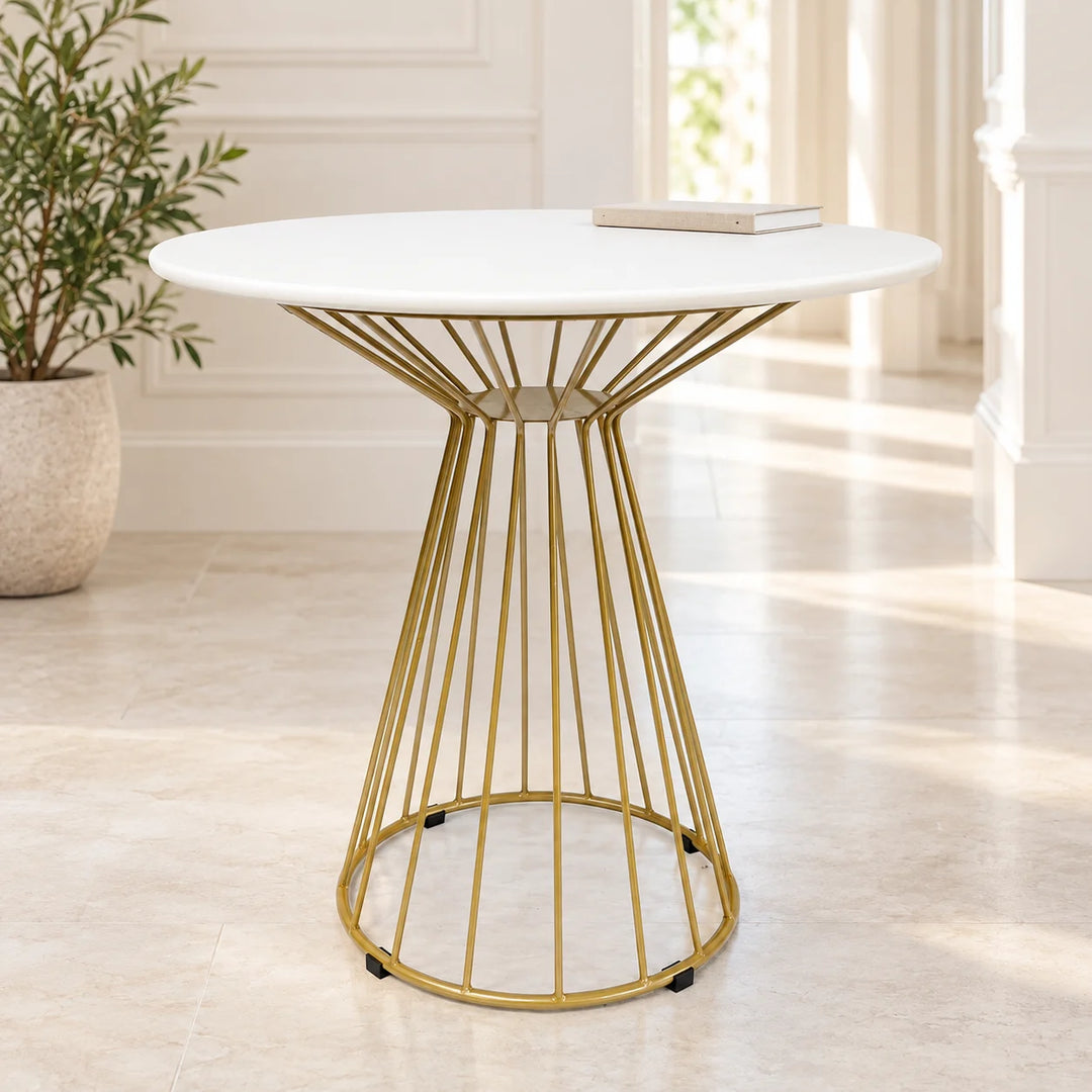 White round side table with gold wire pedestal in a cream hallway beside a natural plant