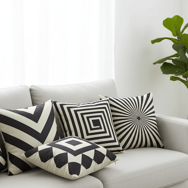 Black and white geometric cushion covers piled on a light grey sofa