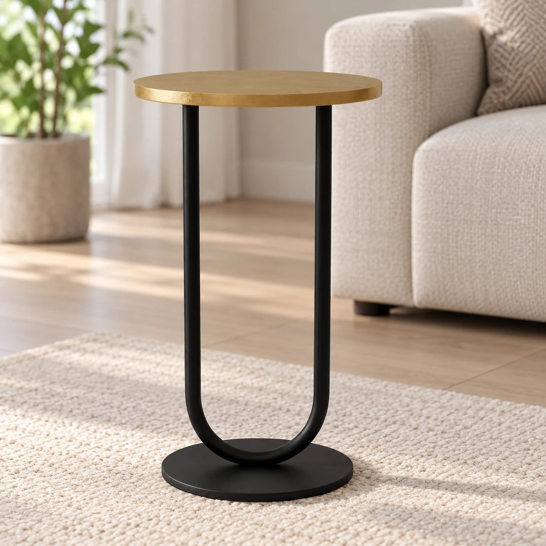 Side table with gold-toned top and black U-shaped support in a daylight room
