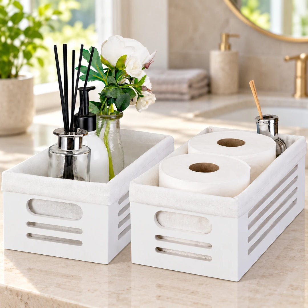Two white tissue organizer boxes with fabric liners and bathroom accessories on a daylight vanity