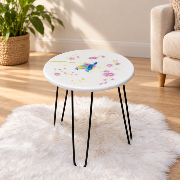 White round table with blue birds and pink flowers on black hairpin legs in a naturally lit room