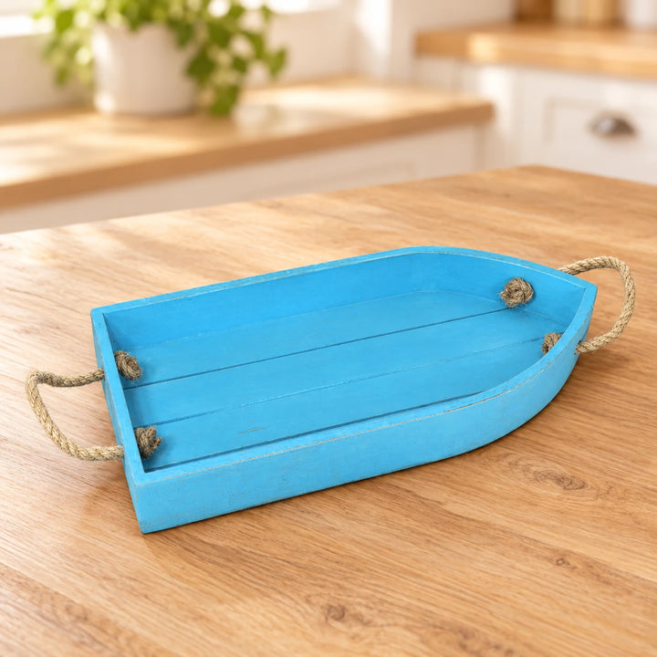 Blue Lagoon boat-shaped wooden serving tray with two rope handles on a sunlit kitchen tabletop