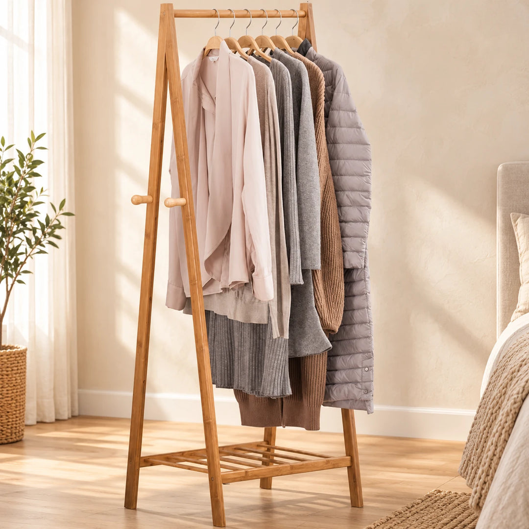 Bragi wooden A-frame clothing rack with side pegs and a single lower slatted shelf in a sunlit bedroom