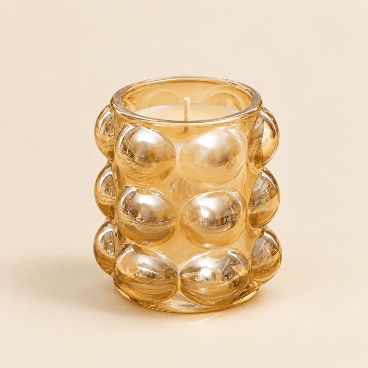 Amber gold bubble glass fancy candle jar, front view on cream background