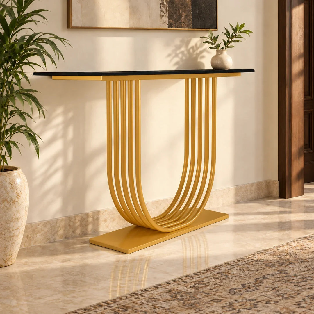 Convex black-top console with Akil Gold powder-coated curved supports and base in a sunlit entryway.