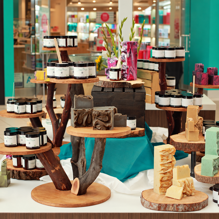 Wooden log slice tree display stand holding jars and soaps at market stall