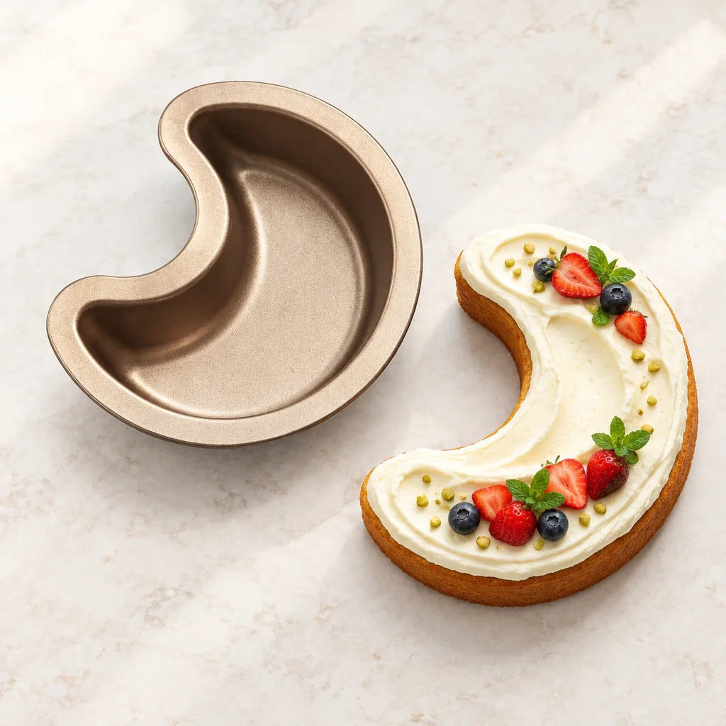 Crescent-shaped baking pan beside a frosted crescent cake