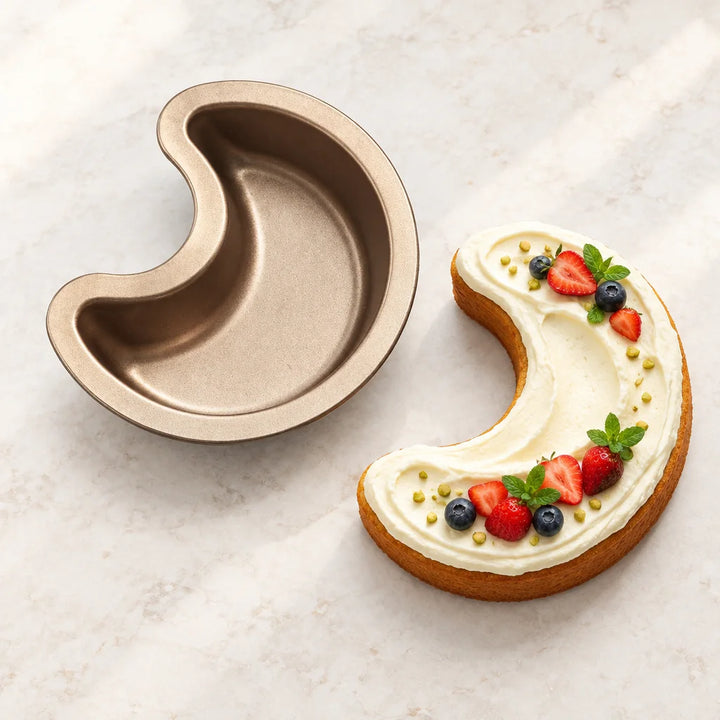 Crescent-shaped baking pan beside a frosted crescent cake