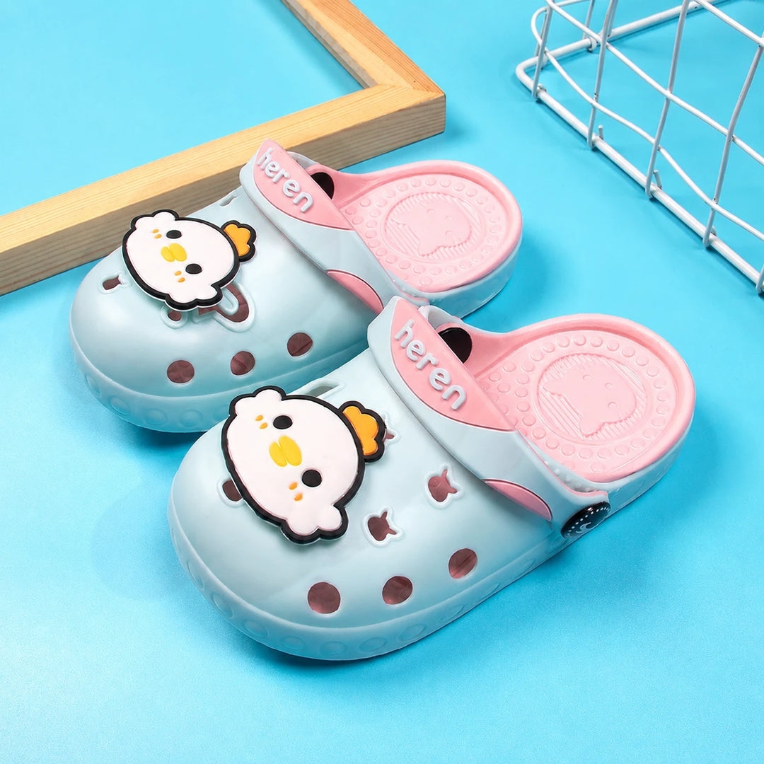 Blue and pink Crickley slippers with chick charms on a turquoise surface