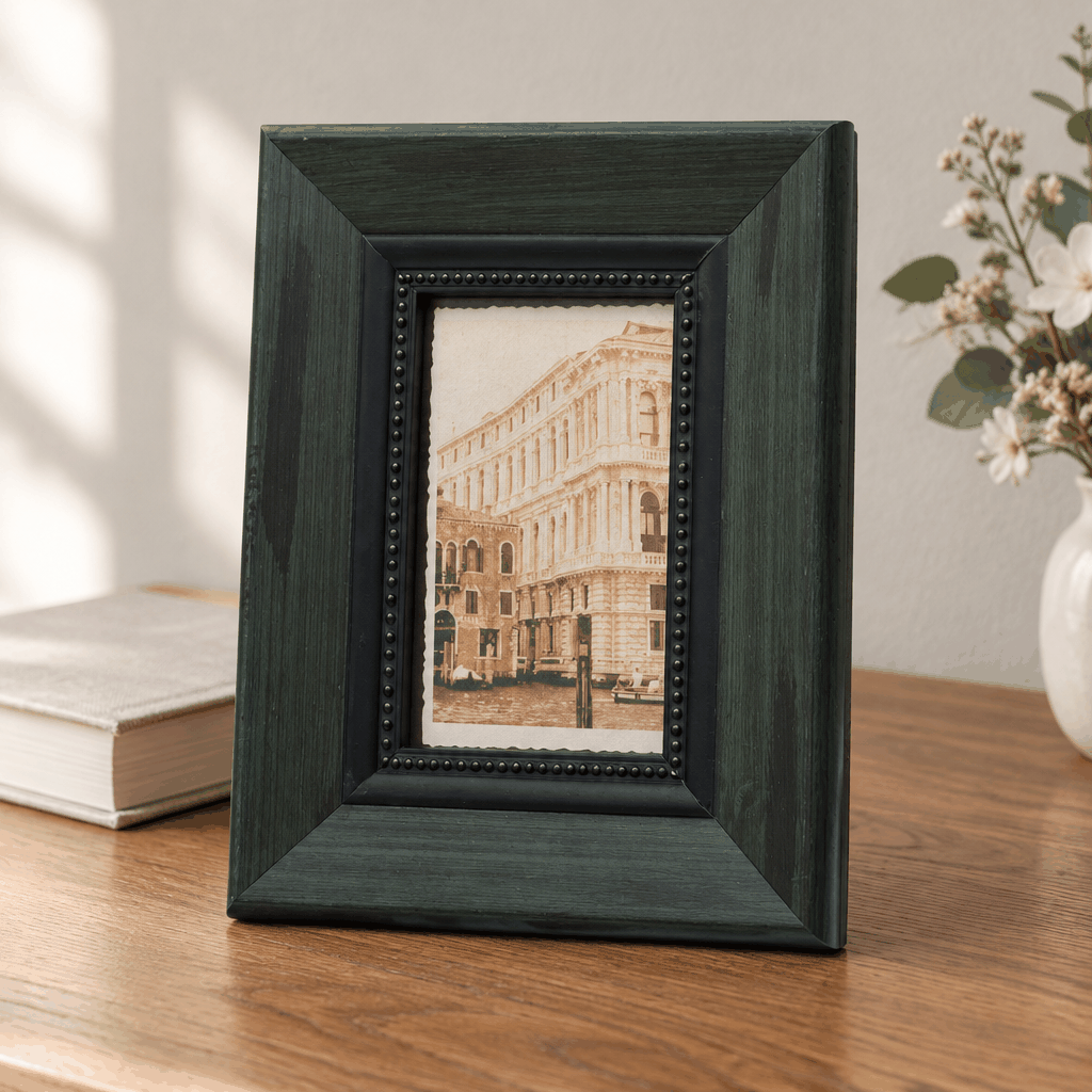 Dark green wide-border photo frame with building photo on white table