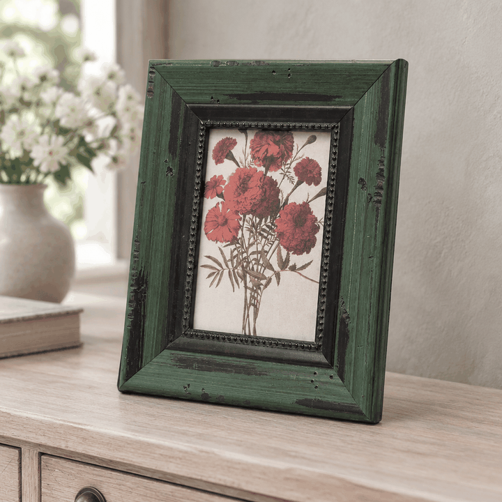 Dark green wooden photo frame with red flower print on dresser