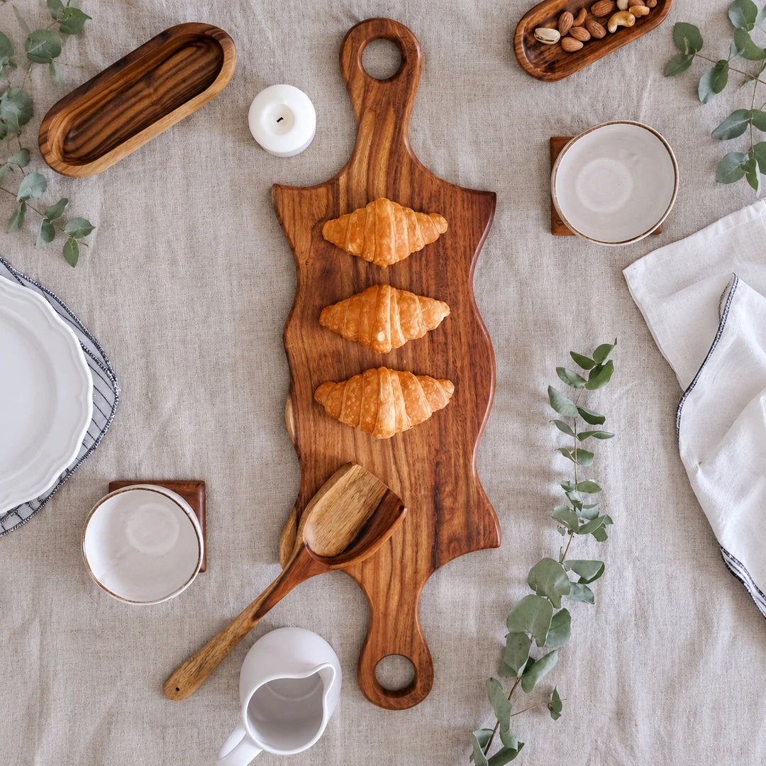 Double swirled wooden platter with handles on white table with herbs