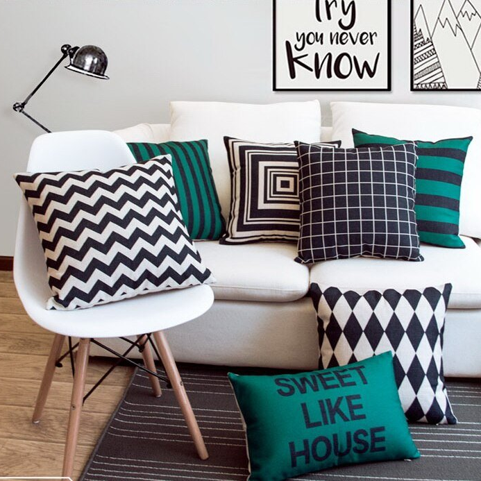 Black, white and teal cushion covers on a white chair and sofa in living room