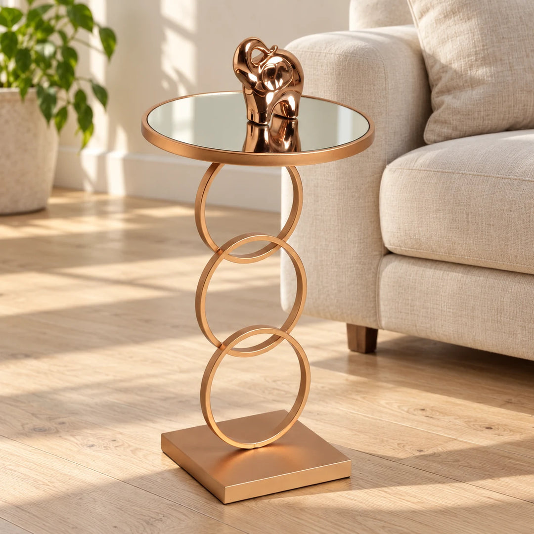Famcir gold round mirrored side table with three interlocking rings beside a cream sofa in a sunlit living room