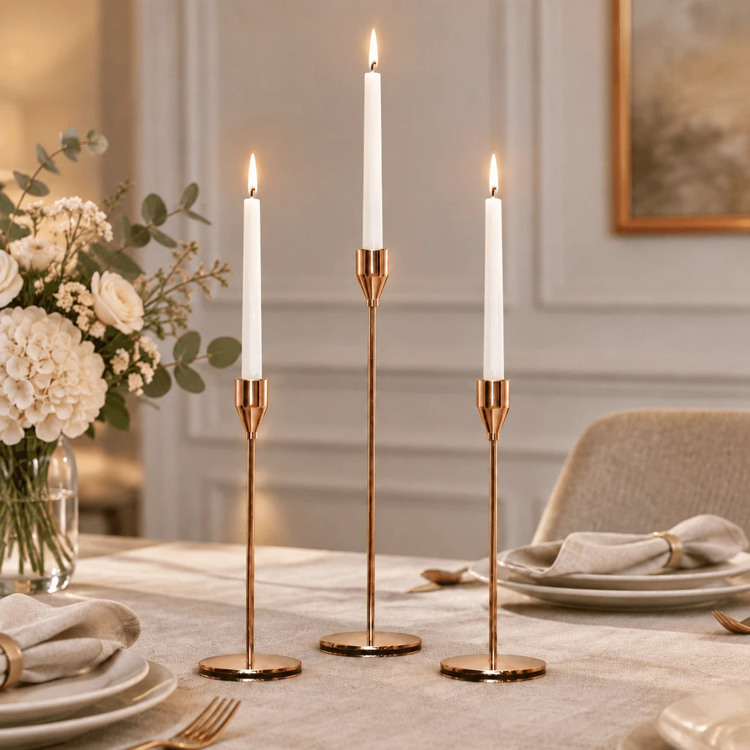 Three gold candle holders with white taper candles on a styled dining table