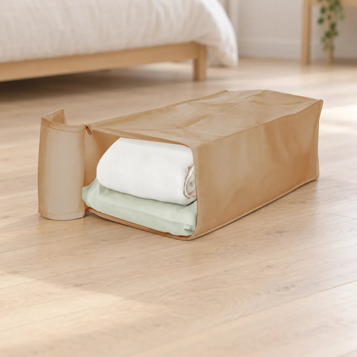 Beige Garmento storage bag with open end flap and folded bedding in a bedroom setting