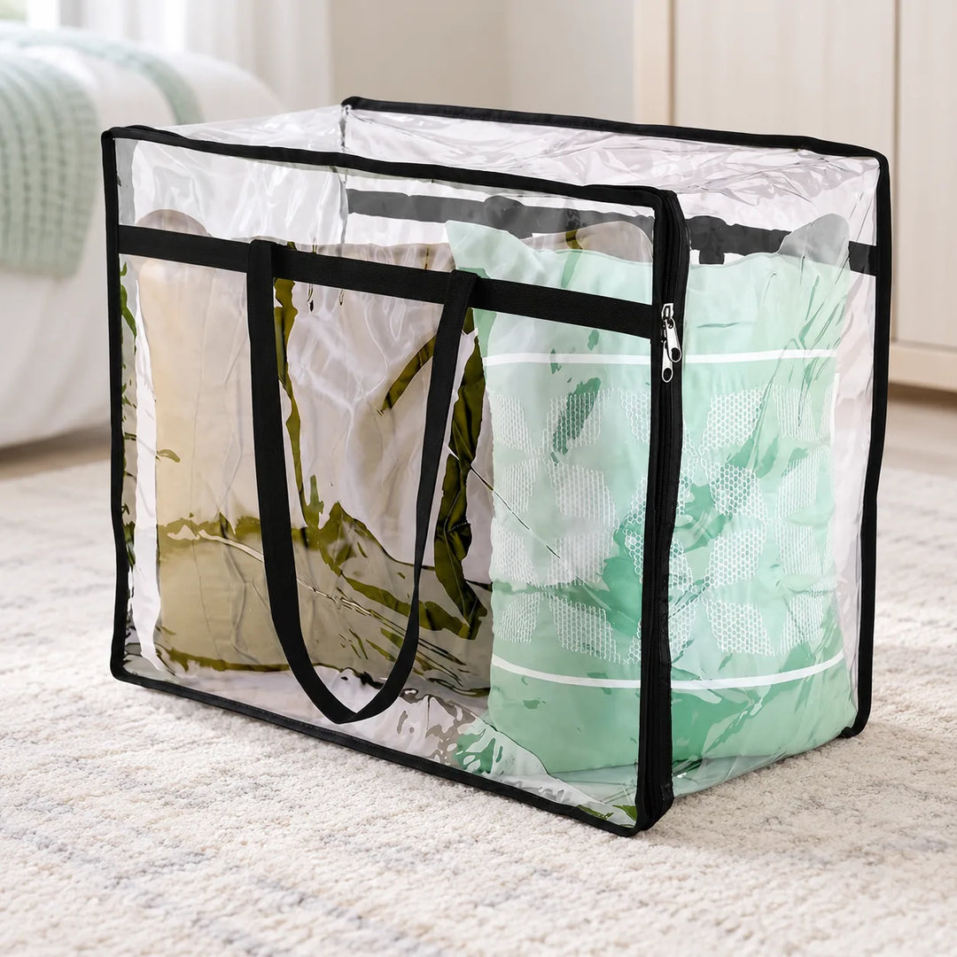 One Glassy clear PVC storage bag with black trim, long handles and double zipper pullers in a bedroom; bedding shown for styling.