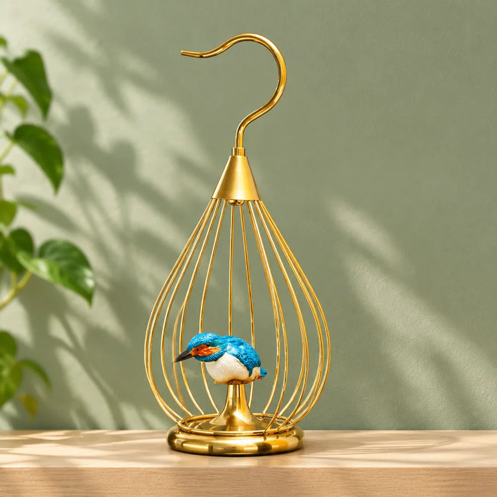 Golden teardrop metal birdcage decor with blue bird on perch against green wall