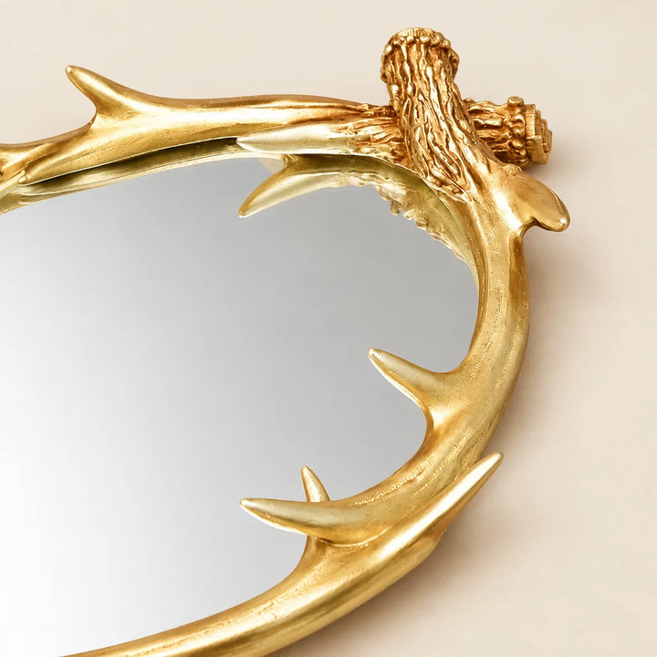 Close-up of gold antler branch frame on oval mirror tray