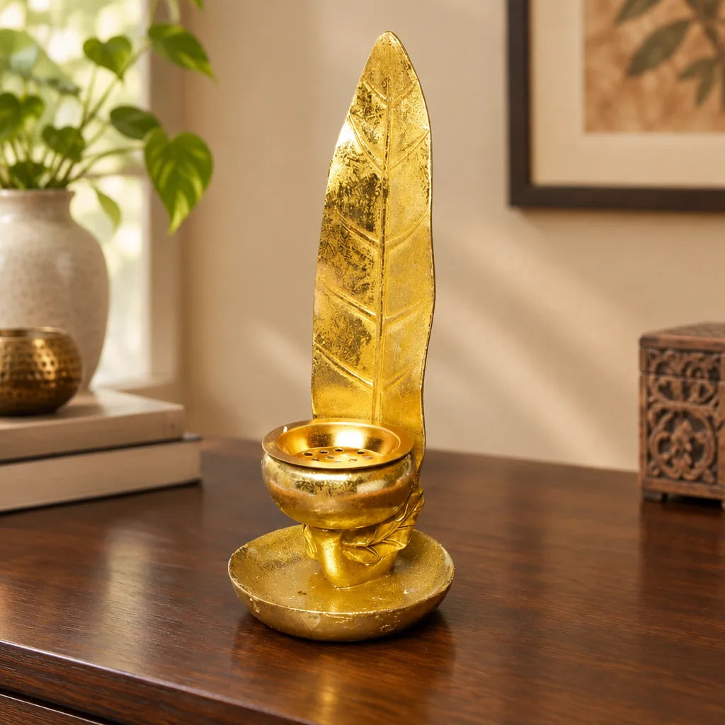 Gold leaf candle holder on wooden sideboard beside books and a potted plant
