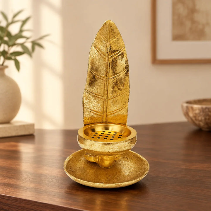 Gold feather candle stand with round dish base on wooden table, front view
