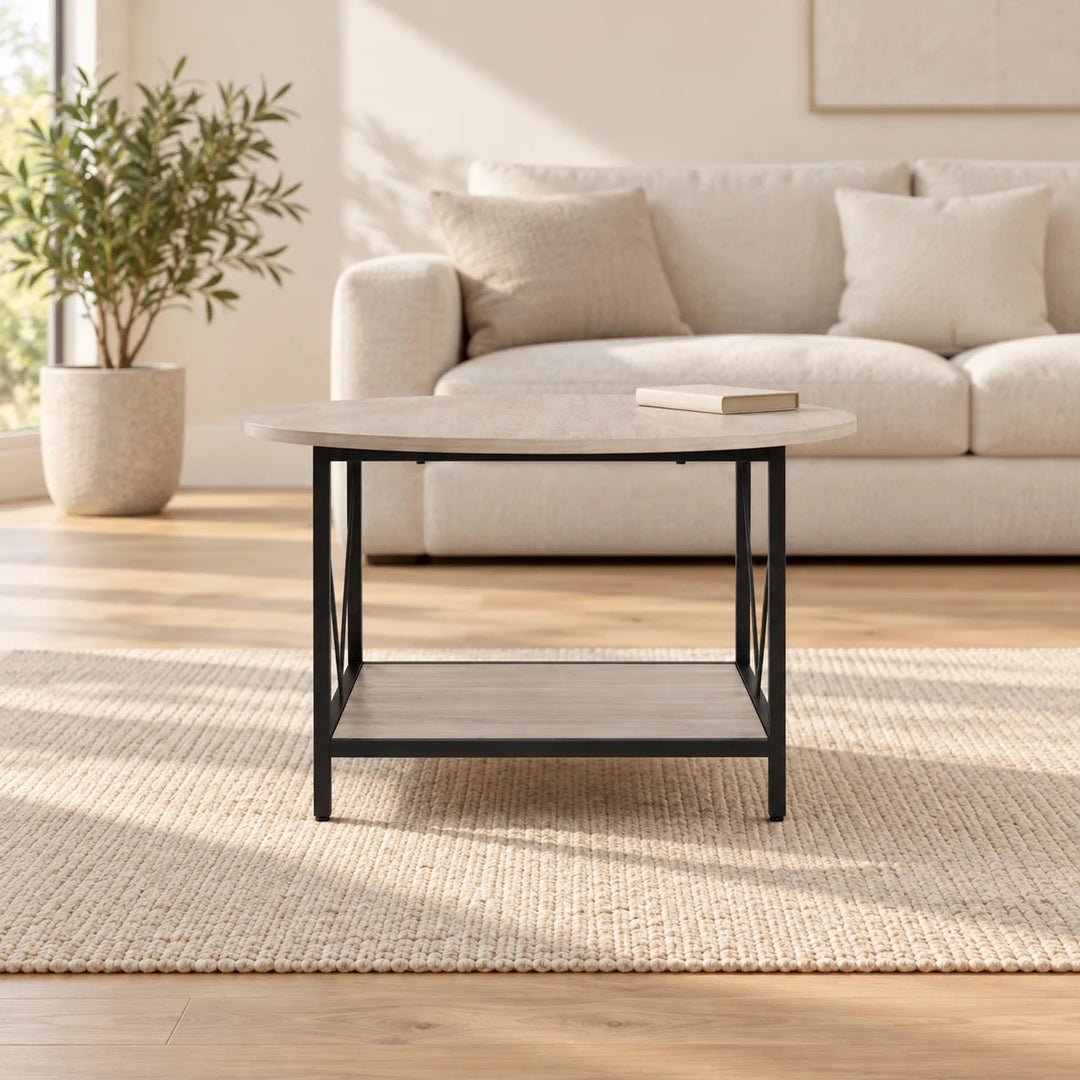 Pale round Granillo coffee table with rectangular lower shelf and black frame in a natural-light lounge with a plant