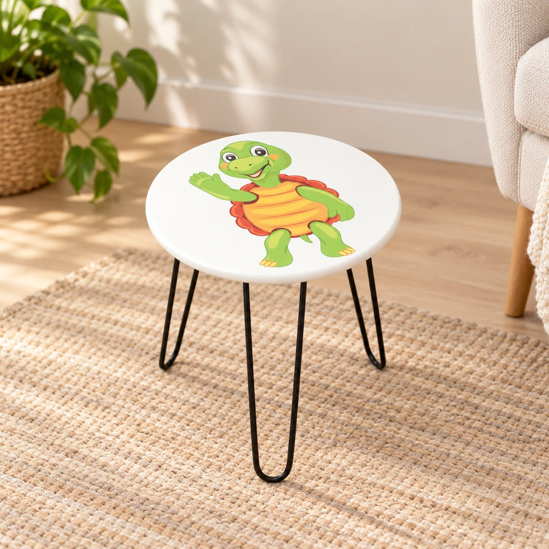 Round white turtle-print side table with three black hairpin legs in a sunlit reading nook