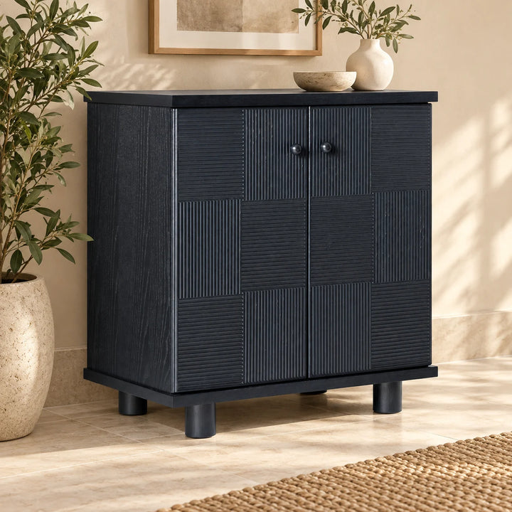 Hazel Reed charcoal cabinet with alternating ribbed doors styled with plants and ceramics