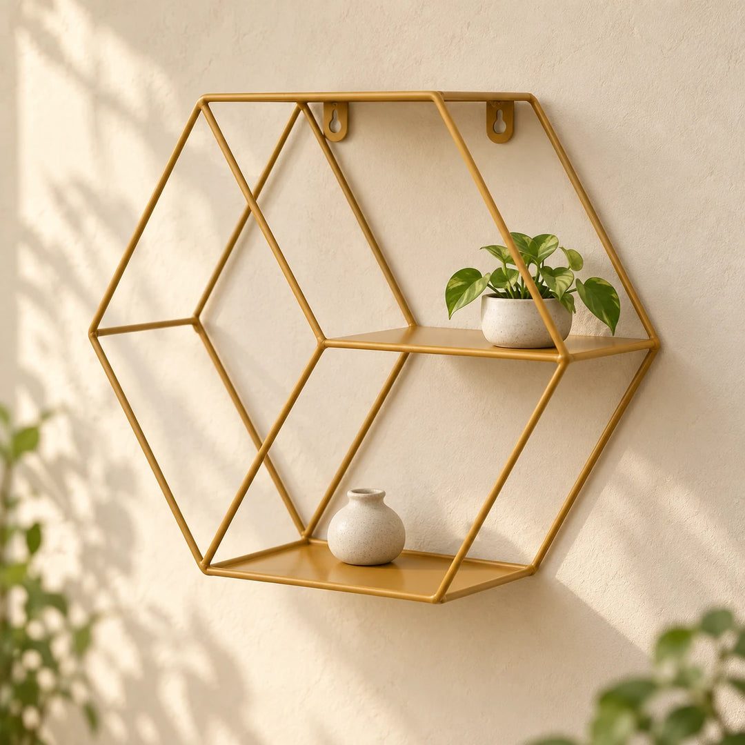 Golden hexagonal metal floating wall shelf with a small plant and neutral ceramic vase in natural daylight