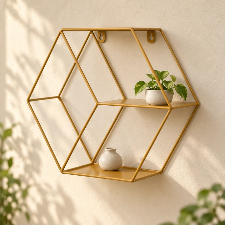 Golden hexagonal metal floating wall shelf with a small plant and neutral ceramic vase in natural daylight