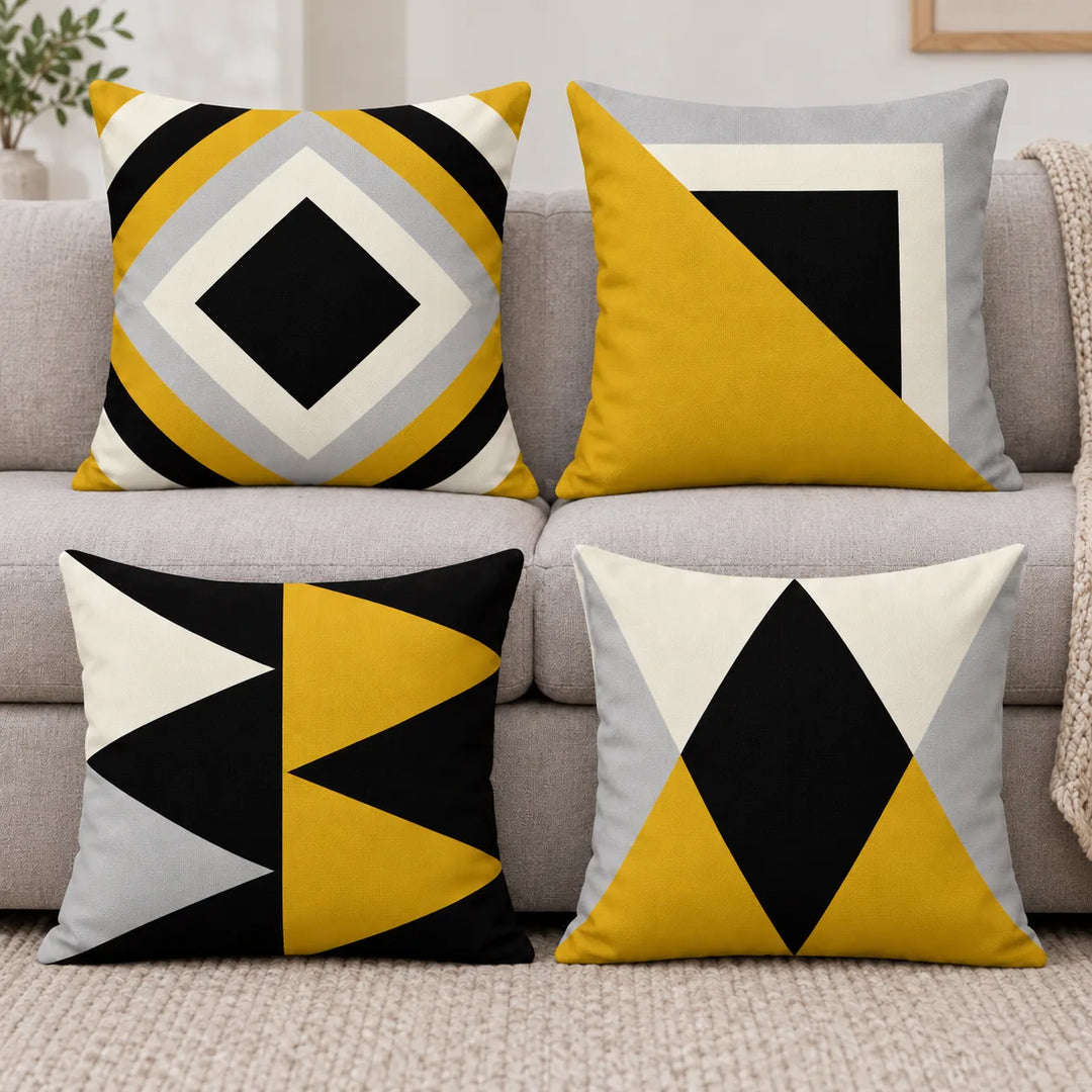 Four geometric cushion covers in black, mustard, grey and ivory with their distinct printed patterns in a living room
