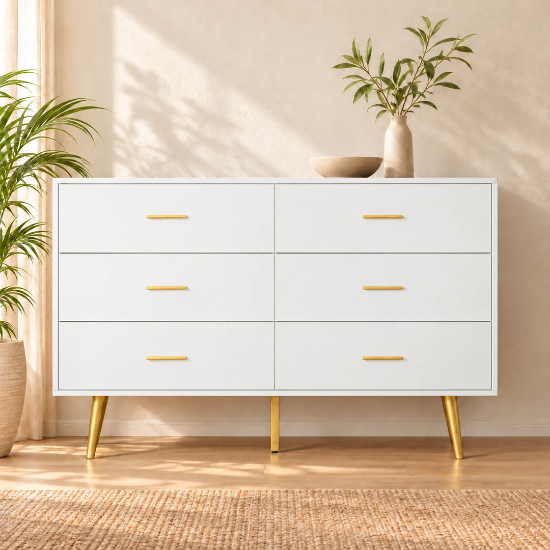 White six-drawer dresser with gold handles and legs in a warm sunlit bedroom