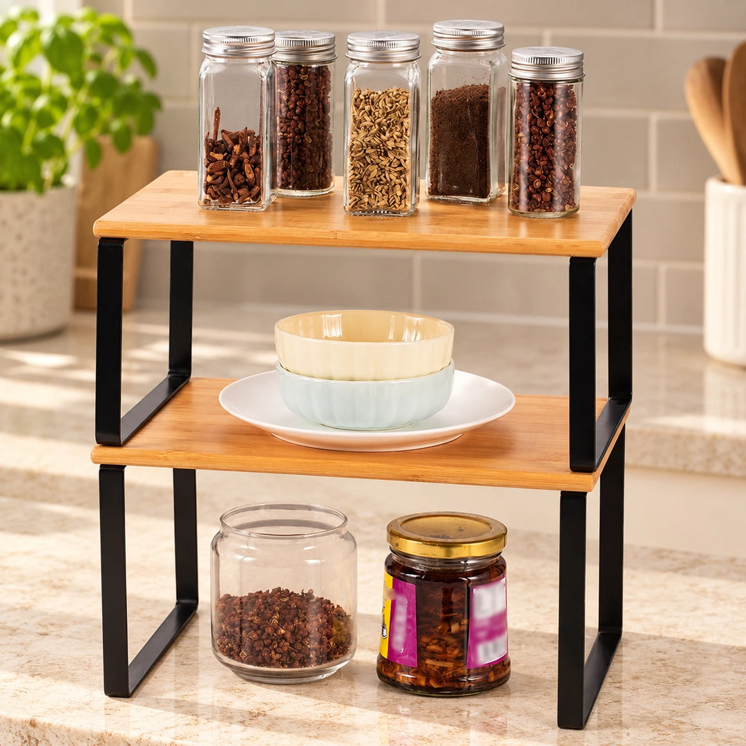Two-tier wooden and black metal kitchen shelf organizer with spices and dishes on a sunlit countertop