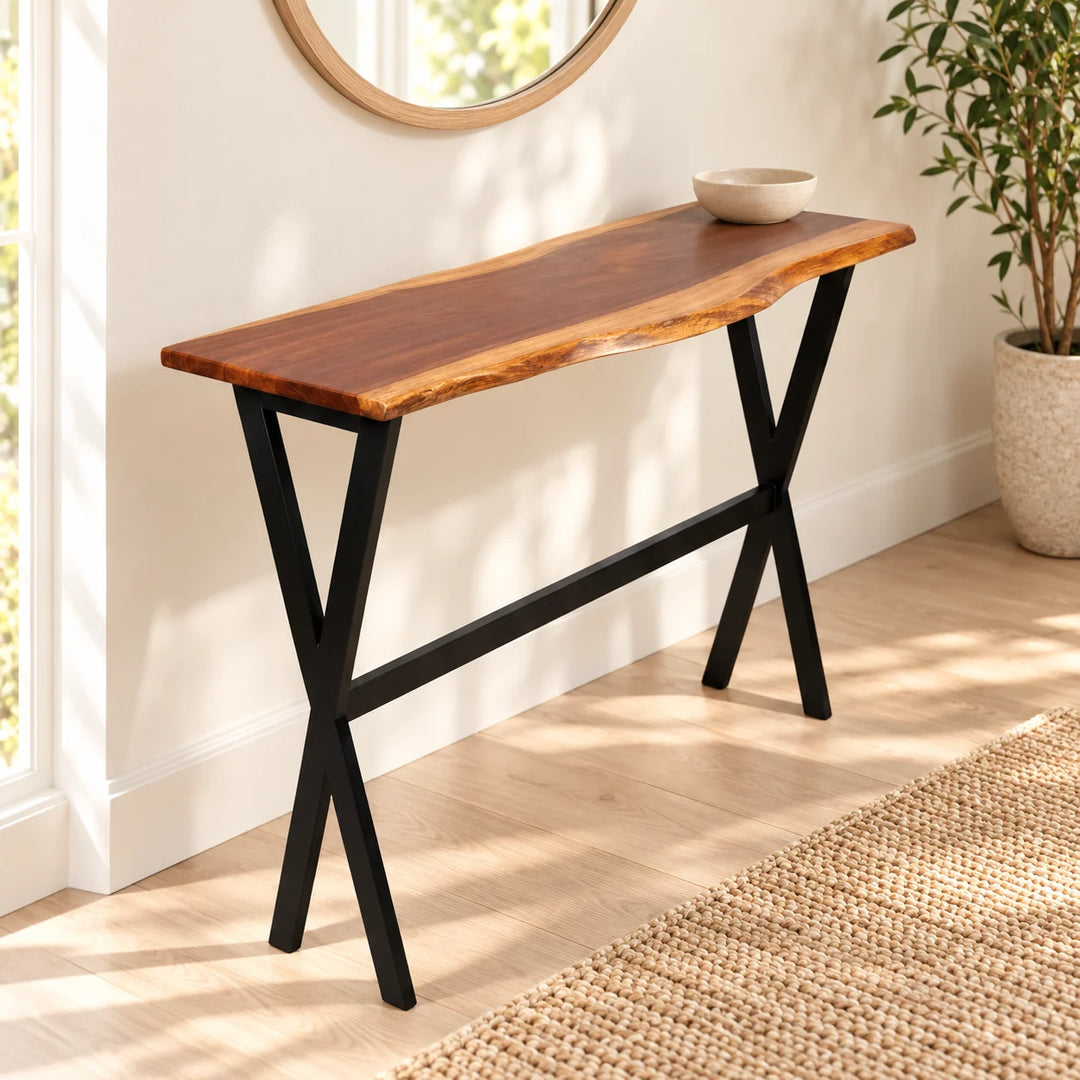 Natural live-edge wooden slim console with black X legs in a cream hallway beside a natural plant