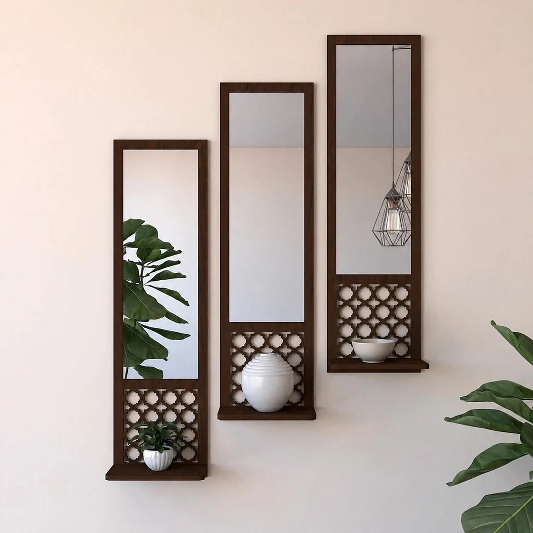 Three dark wood wall mirrors and lattice display shelves with a plant, white vase and plain bowl