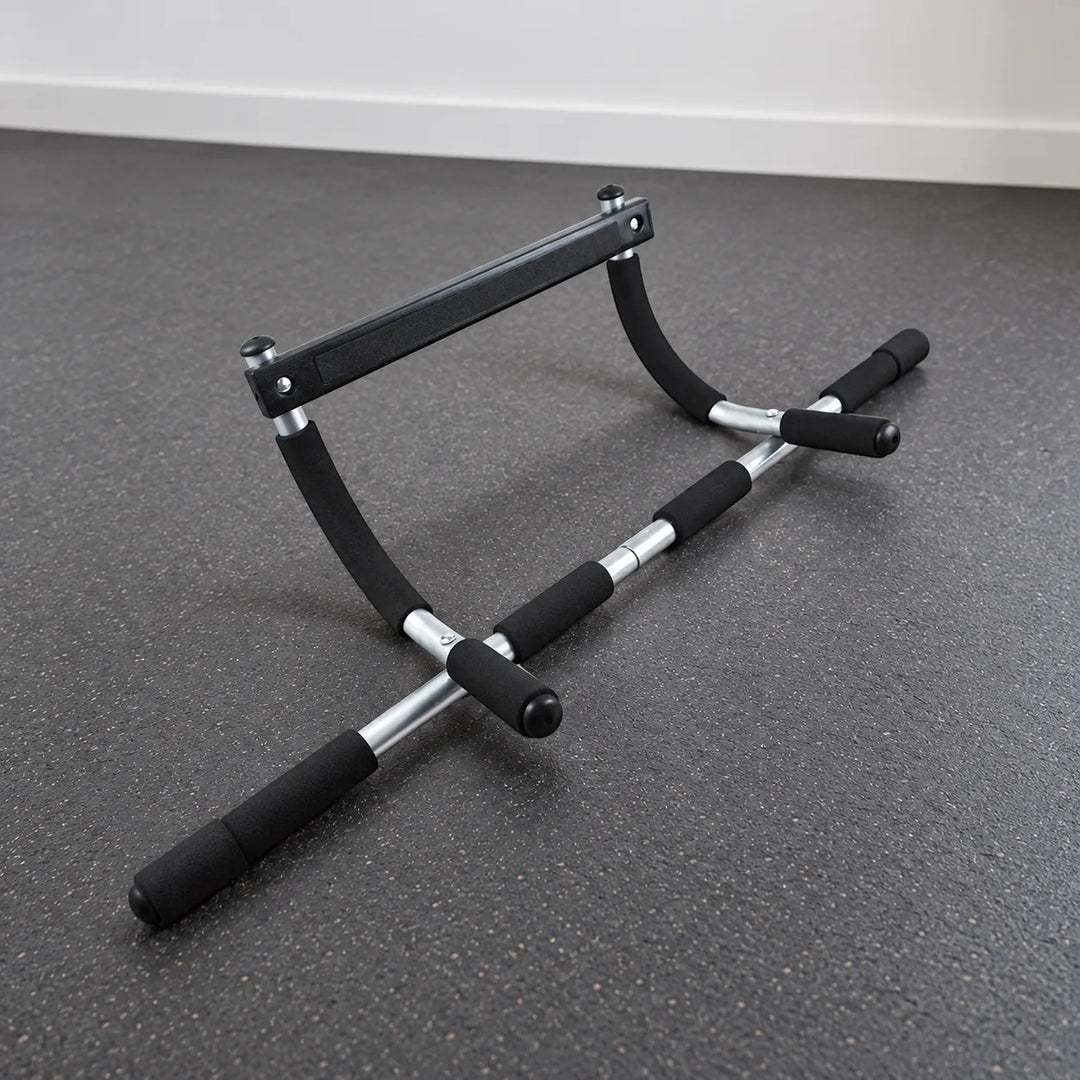 Black and silver Mobile Gym Bar with foam grips resting unattached on a home gym floor