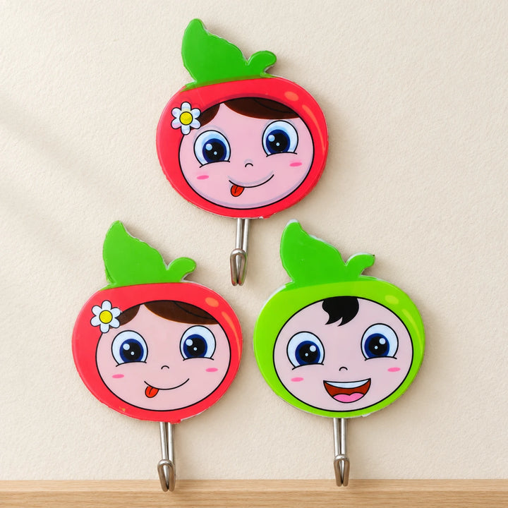 Three colourful face-design hooks on a textured wall