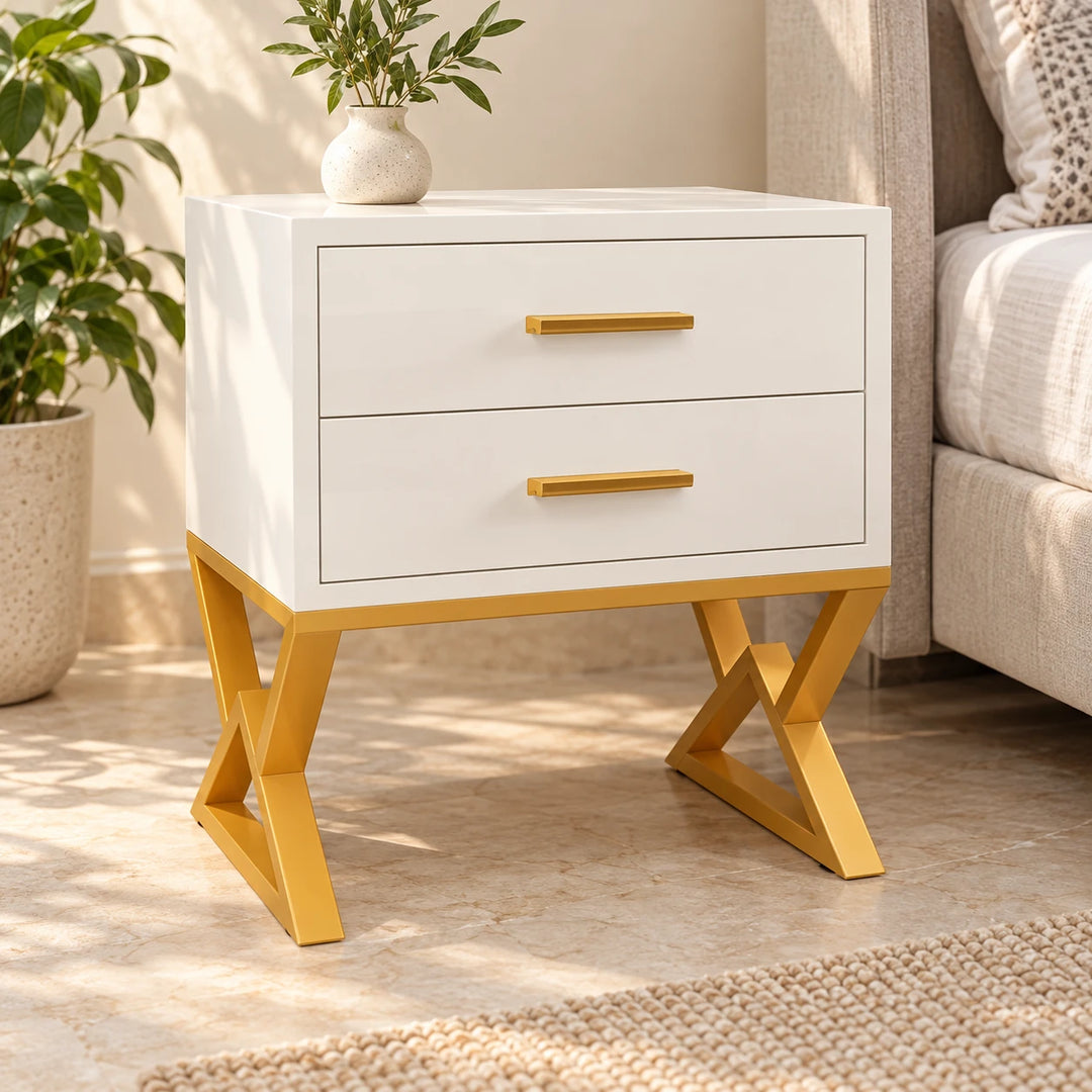 Nugatory white two-drawer bedside table with gold powder-coated crossed legs in a daylight bedroom